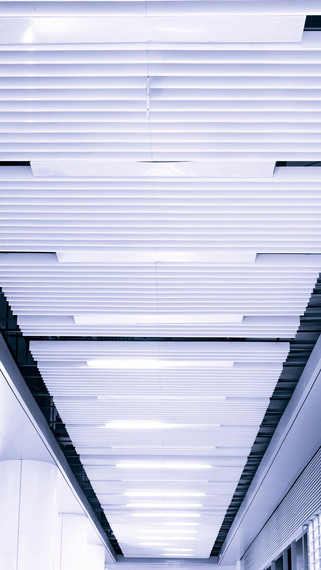 Deretan lampu panel linear di plafon koridor modern gedung perkantoran