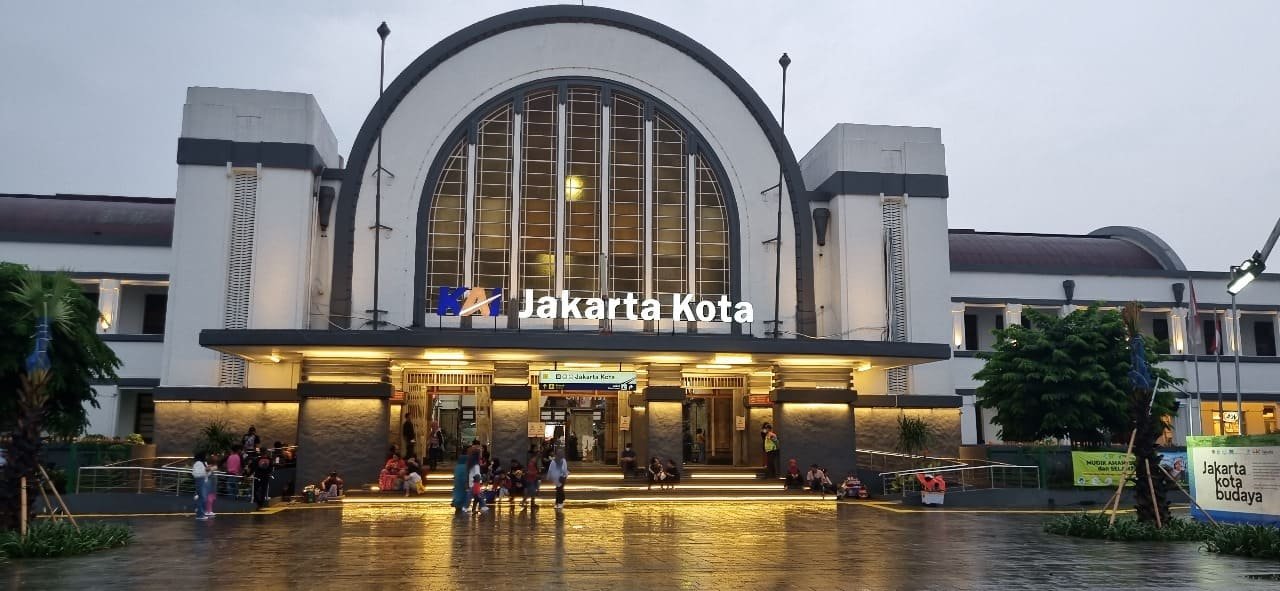 Fasad bertuliskan KAI Stasiun Jakarta Kota tampak terang pada malam hari